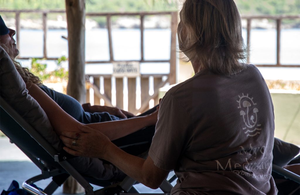 Facilitator offers comforting touch during psilocybin retreat integration circle.