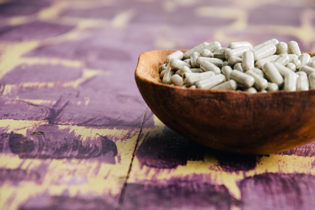 Psilocybin mushroom capsules in a wooden bowl at a MycoMeditations therapeutic retreat in Jamaica.