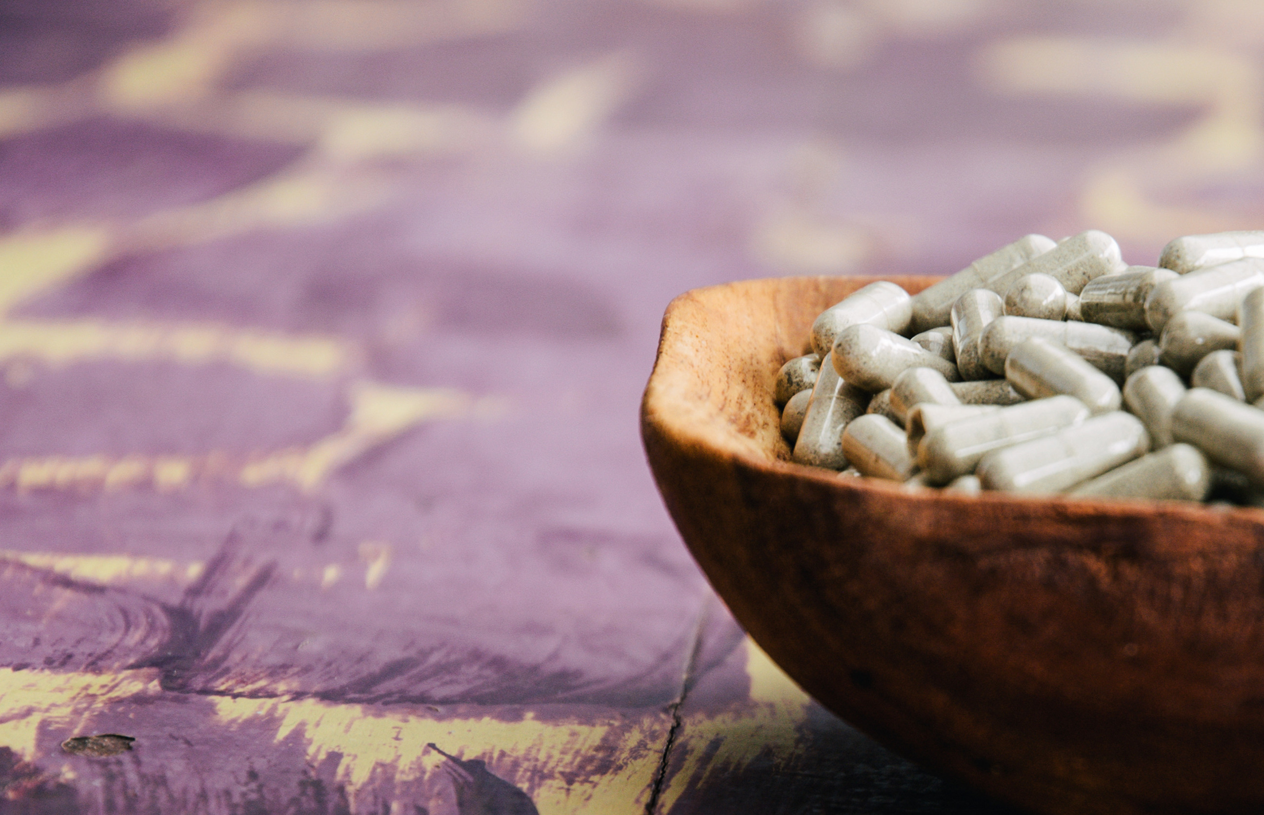 psilocybin mushroom capsules in wooden bowl at mycomeditations