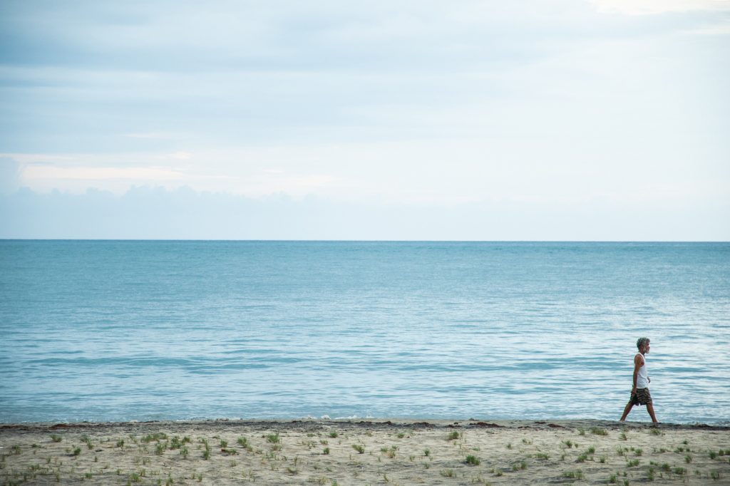 man walks on the beach with the sea in the background at mycomeditations