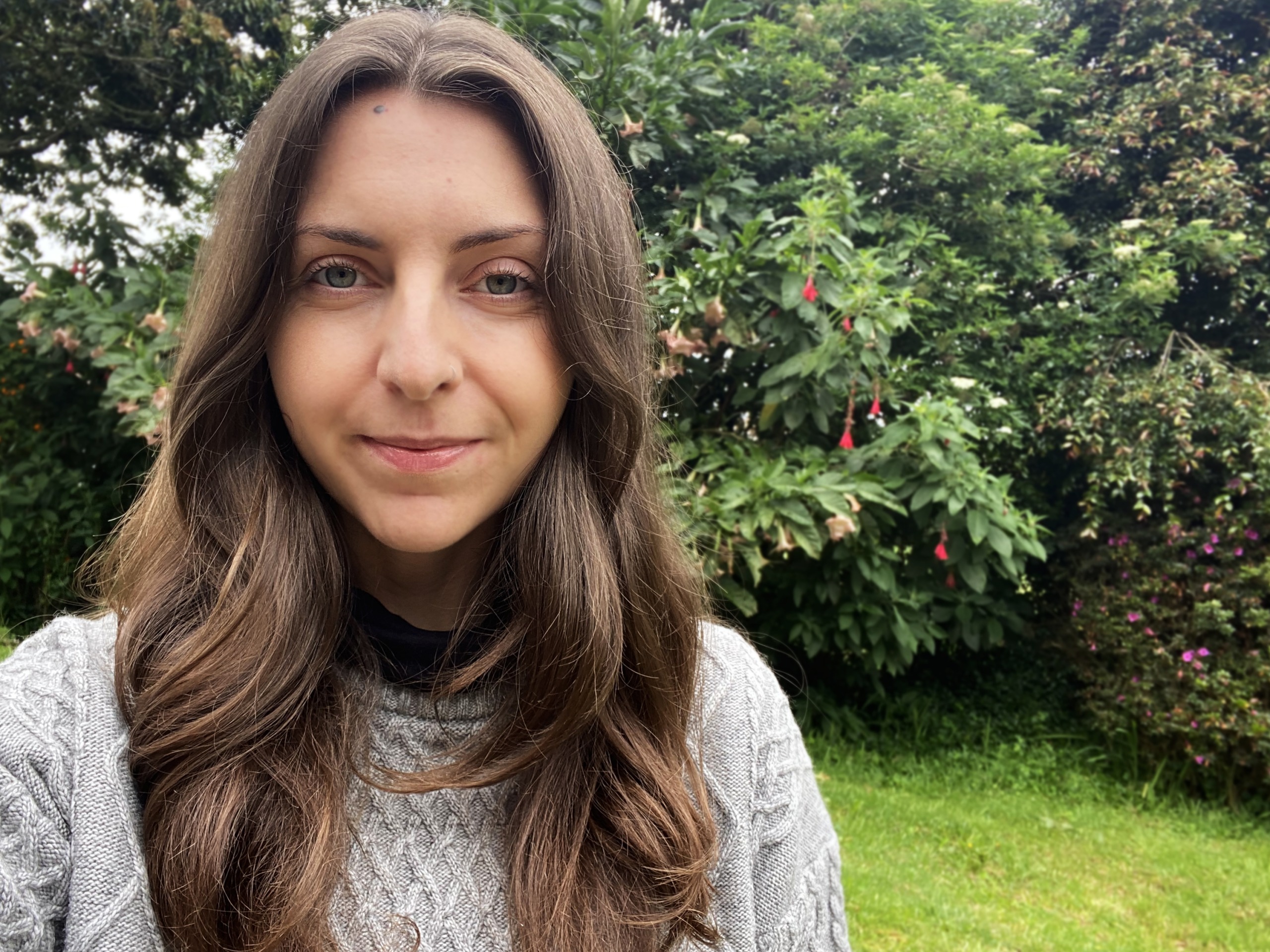 MycoMeditations blog writer, Mags Tanev, standing outdoors in a green space.